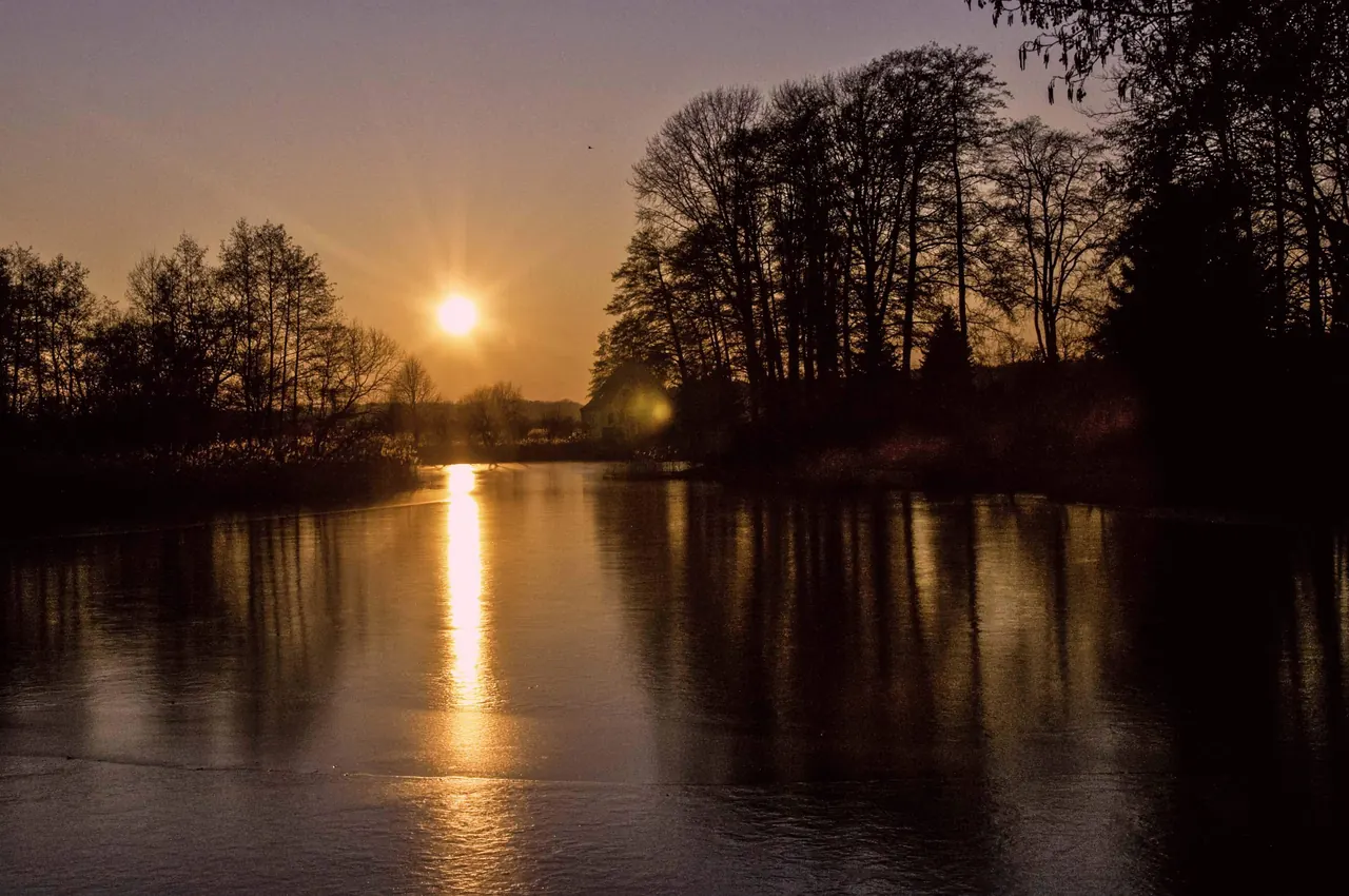 Golden sunset reflected on dark water, symbolizing clarity after separating present reality from old emotional patterns
