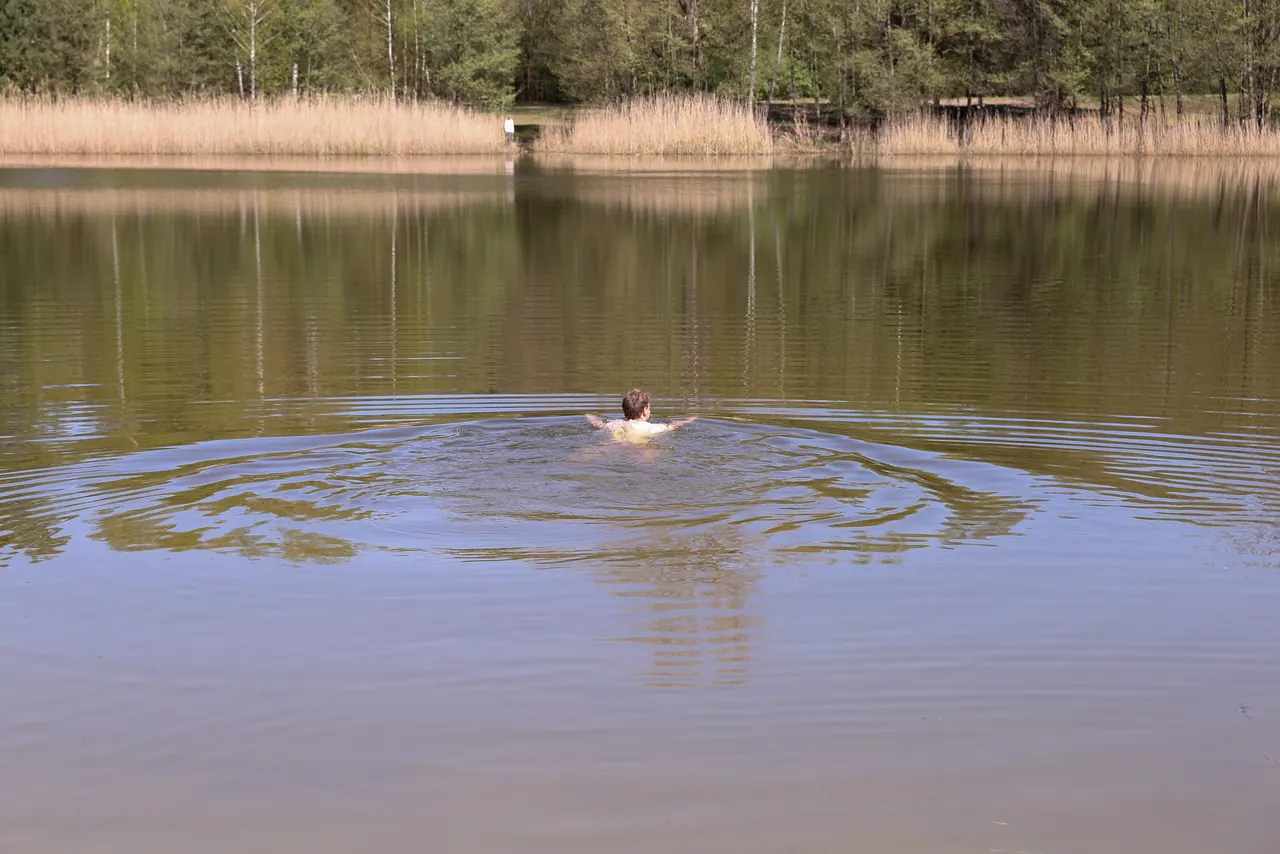 Person swimming through reflected water and ripples, symbolizing how present experiences mix with old emotional patterns